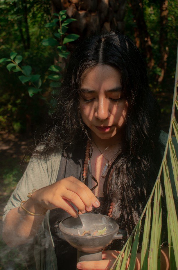 Flores, vela encendida y círculo de piedras
